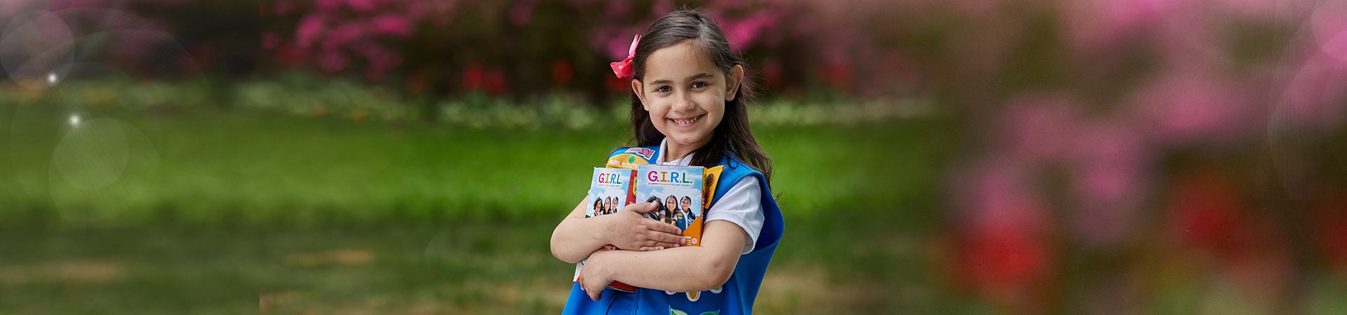  group of daisy girl scouts holding hands in uniform blue apron vest with patches and badges 