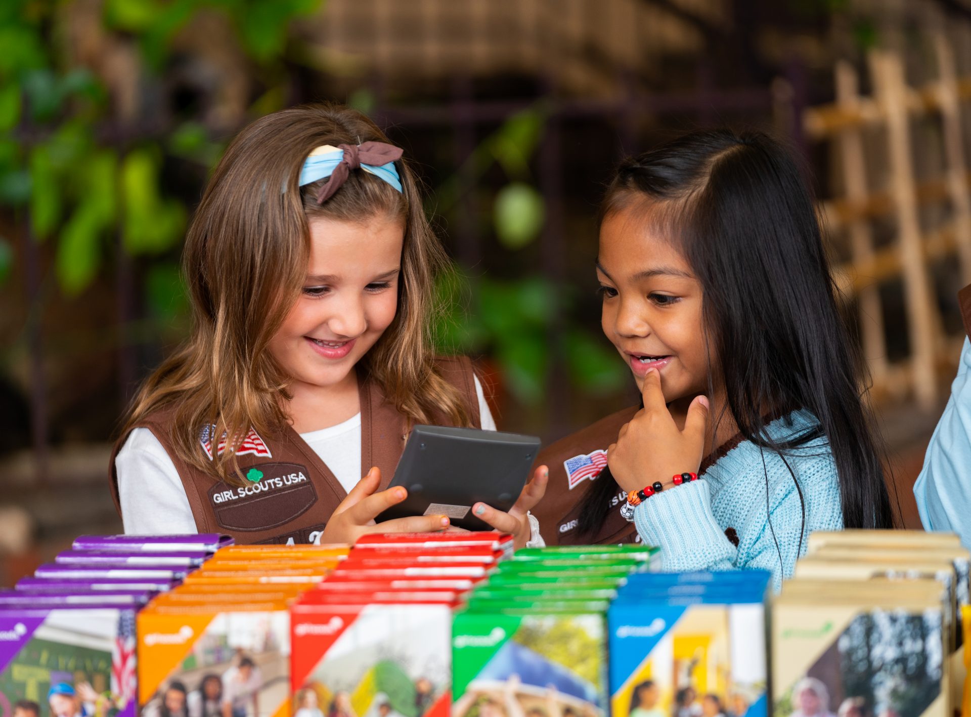 volunteer with junior girl scouts at outside cookie booth smiling