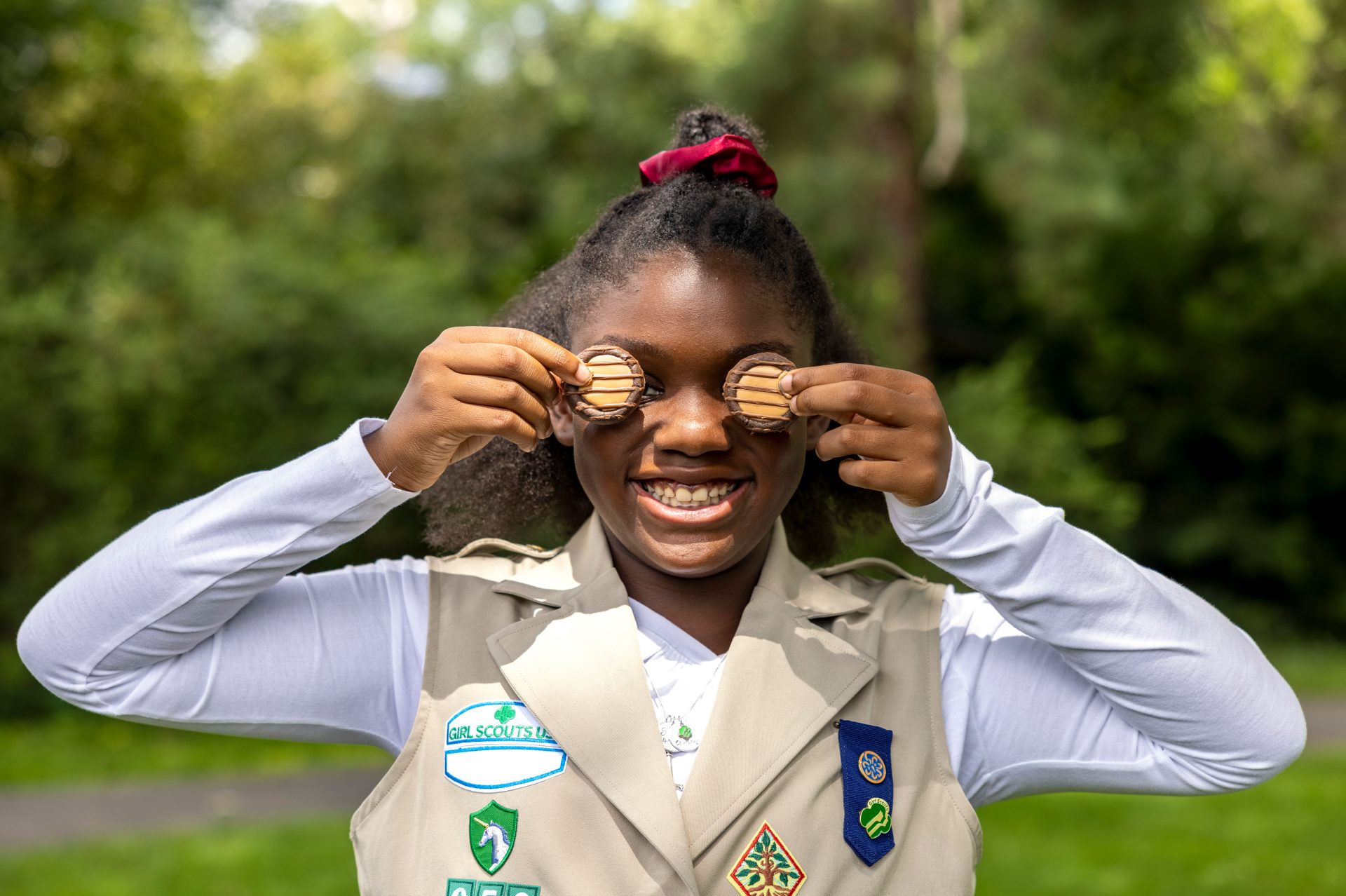 volunteer with junior girl scouts at outside cookie booth smiling